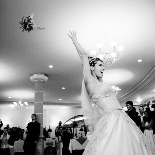 Noiva jogando o buquê numa festa, em preto e branco